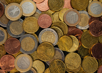 Many euro cents with coins of one and two euros lie.
