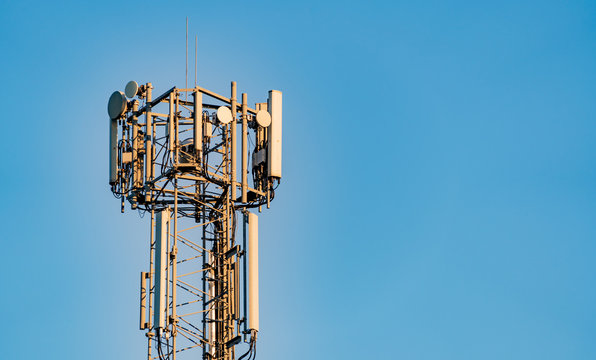 Communications, cell, mobile tower in UK set against a bright blue sky with copy space