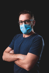 Adult person with protective face mask posing on a black background - social issues with virus and contagious safety measures.