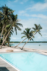 Fototapeta na wymiar Amazing tropical landscape with blue swimming pool, beach and palm tree. Top travel destination, commercial dream life, hot summer days.