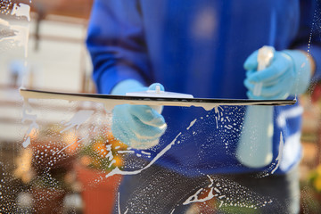 housekeeping: cleaning the windows, Window cleaner using a squeegee, sponge and soap suds to wash a window