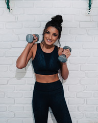 Young woman holding dumbbells and smiling