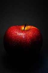 red apple with drops of water on a black background