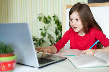 Online education concept.
Distance learning online education. Schoolgirl studying at home with laptop notebook and doing school homework. Communication,
social distance during quarantine