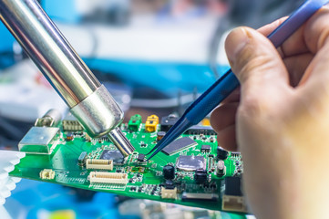 Technical support worker drops the fee PCB. Soldering iron. Tweezers