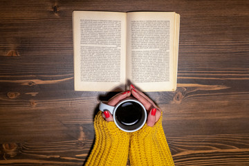 Shot from above of woman drinking coffee while reading a book
