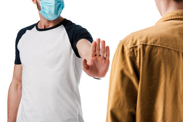 cropped view of man in medical mask showing stop gesture near guy isolated on white