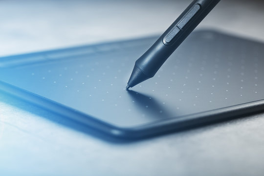 Pen with a graphic tablet in the hands of the designer, close-up. Gadget for art and work.