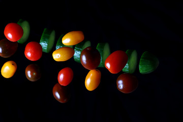 colored juicy tomatoes and sliced cucumber in a drop on a dark background