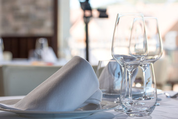 Disparo de cerca de una mesa de restaurante con vasos vacíos y un plato. Mirada más cercana.  Mesa del restaurante con servilleta, plato y vasos. 