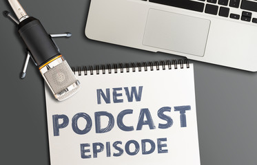 top view of podcast recording equipment on desk with words new podcast episode written on note pad