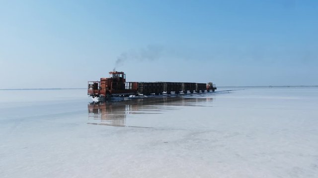 Old train rides on the railway laid in the water through the salt lake. train travels from water. Mined salt in Lake Burlin. Altai. Bursol. Russia. August 2019 