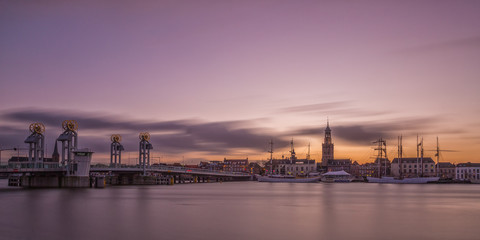 A view on the hanseatic city Kampen, in the Netherlands. Evening skyline photo with Dutch church and towers, its bridge, and some (sailing) ships. - obrazy, fototapety, plakaty