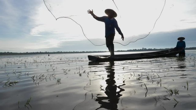 Silhouette of Asian fisherman with fishing net casting fish by throwing fishing net into the lake in morning sunshine.Fish is nature food from river or lake at rural in developing country
poor living.