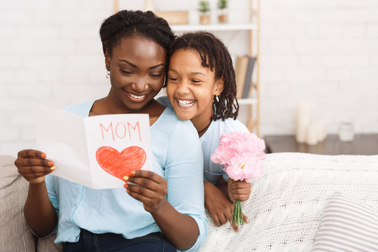 Black girl congratulating her mom with flowers and card