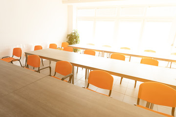 Empty desks and chairs in high key cafeteria room