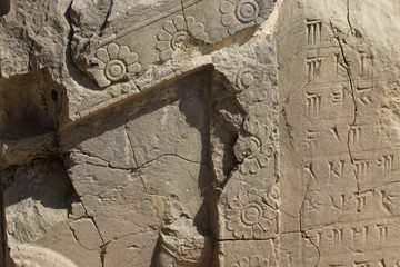 fragment kamiennej rzeźbionej ściany z dekoracjami i pismem klinowym wśród ruin starożytnego miasta persepolis - obrazy, fototapety, plakaty