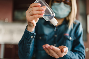 Coronavirus. Sanitizer gel. Business woman working in home, quarantine. Cleaning hands antibacterial gel to eliminate germs. Stay at home. Girl learns, using laptop. Freelance. Prevent Covid-19 virus.