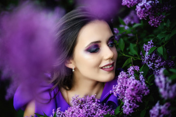 portrait of a beautiful young girl in a purple dress in bloom of lilac