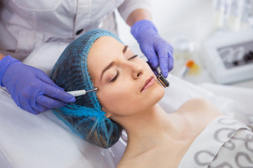 Cosmetology. Beautiful Woman At Spa Clinic Receiving Stimulating Electric Facial Treatment From Therapist. Closeup Of Young Female Face During Microcurrent Therapy.