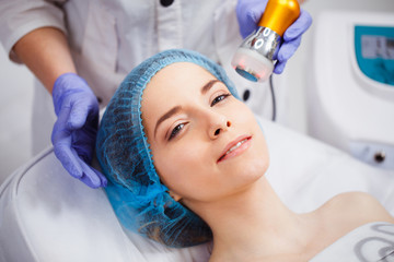 Naklejka premium The procedure of photoepilation in the beauty salon. A young woman is removed unwanted hair on her face. Hardware cosmetology. Close up
