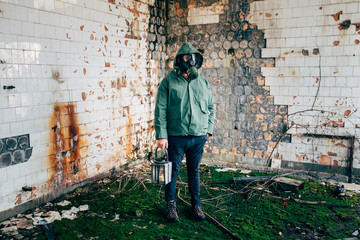 Fototapeta na wymiar Dramatic portrait of a man wearing a gas mask in a ruined building. 