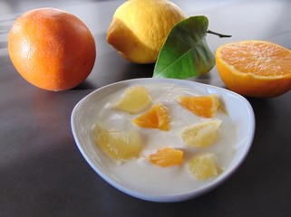 Yoghurt with citrus fruits in a bowl. Sour cream, yogurt with fresh orange and lemon, close up.