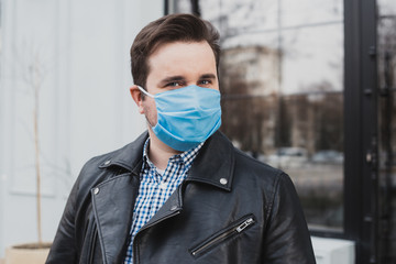 young man wearing mask on a background of closed cafe, coronavirus, illness, infection, quarantine, medical mask