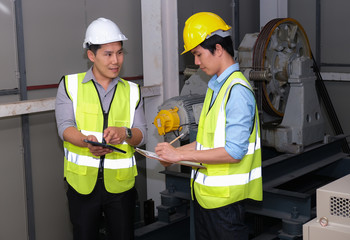 Senior engineer point to the tablet and explain to junior engineer on how to operate lift Feeling...