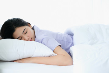 Fototapeta na wymiar Young beautiful Asia woman sleeping and enjoy on the soft bed at the modern bedroom and feeling relaxing in the morning. Hugging soft white pillow. Resting, good dream and sleep concept.