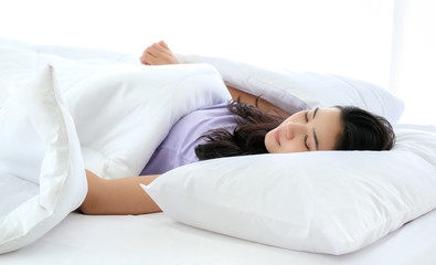 Young beautiful Asia woman sleeping and enjoy on the soft bed at the modern bedroom and feeling relaxing in the morning. Hugging soft white pillow. Resting, good dream and sleep concept.