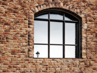 large arch-shaped window with binding and reflection of a lantern in glass on a stone wall. Copy space for inscriptions. The concept of self-isolation and stay home