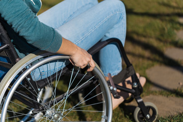 Close up of a young woman in a wheelchair while walking in a park on a sunny day. Recovery and...