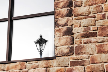 Part of a window with binding and reflection of a lantern in a glass on a stone wall of a country...