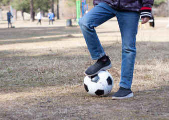 a boy in a red hood plays soccer with a soccer ball on the street