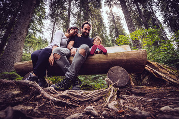 happy family sitting du of a wooden bench in the middle of the forest