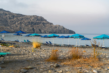 Parasols and empty sun beds on a stone beach