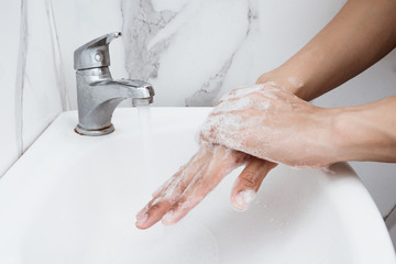Young man washing hands over sink in bathroom, closeup, Corona virus or Covid-19 prevention, hygiene to stop.