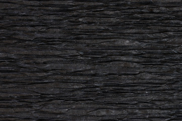 Background of black pressed corrugated paper with a horizontal texture taken close up