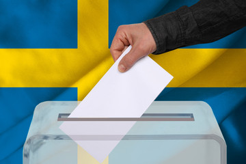 Fototapeta premium male voter drops a ballot in a transparent ballot box against the background of the national flag of Sweden, concept of state elections, referendum