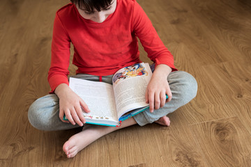 Little boy reading book sitting on floor. Home study on quarantine concept