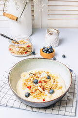 Morning healthy breakfast bowl with yogurt, muesli, blueberry, banana, coconut on the white background.