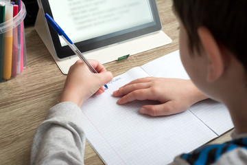 Close-up boy studying at home with tablet and doing school homework. Distance learning online...