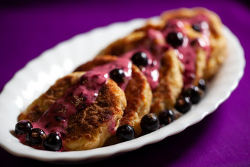 Cottage cheese pancakes with blueberries poured with yogurt and with honey on white plate. Delicious Homemade Cheese Pancake. Healthy homemade traditional Ukrainian dishes.