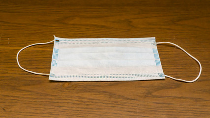 A 3 layers surgical facial mask on wooden background.