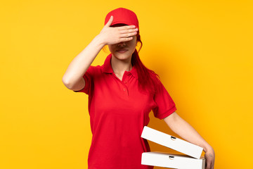 Pizza delivery girl holding a pizza over isolated background covering eyes by hands. Do not want to...