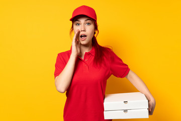 Pizza delivery girl holding a pizza over isolated background with surprise and shocked facial expression