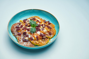 Appetizing pancakes with jam, sour cream and pumpkin in a blue plate isolated on grey background. Tasty breakfast food