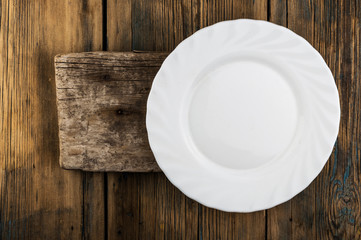Empty white plate on wood background, top view