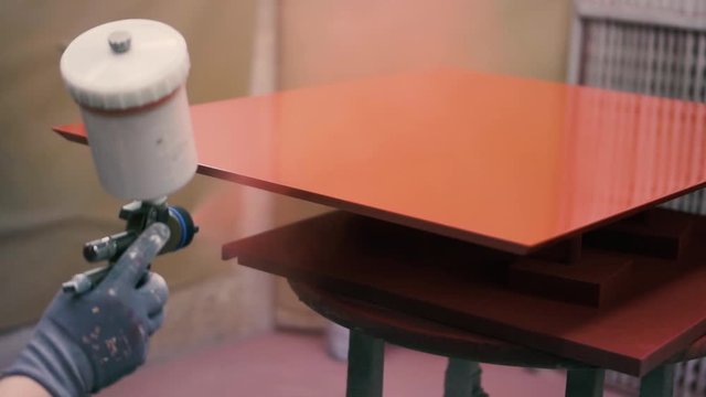 Spray Painting A Wooden Board Using A Spray Gun With Red Paint In Slow Motion - Closeup Shot